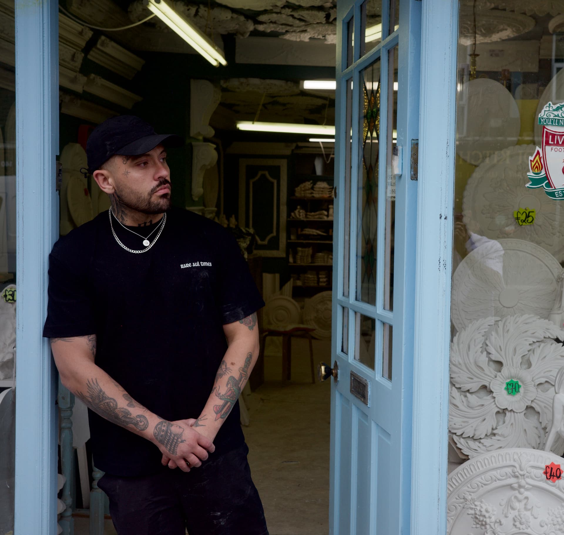 Model wearing the black RAT Penny Coin Tee in a Dublin shopfront doorway